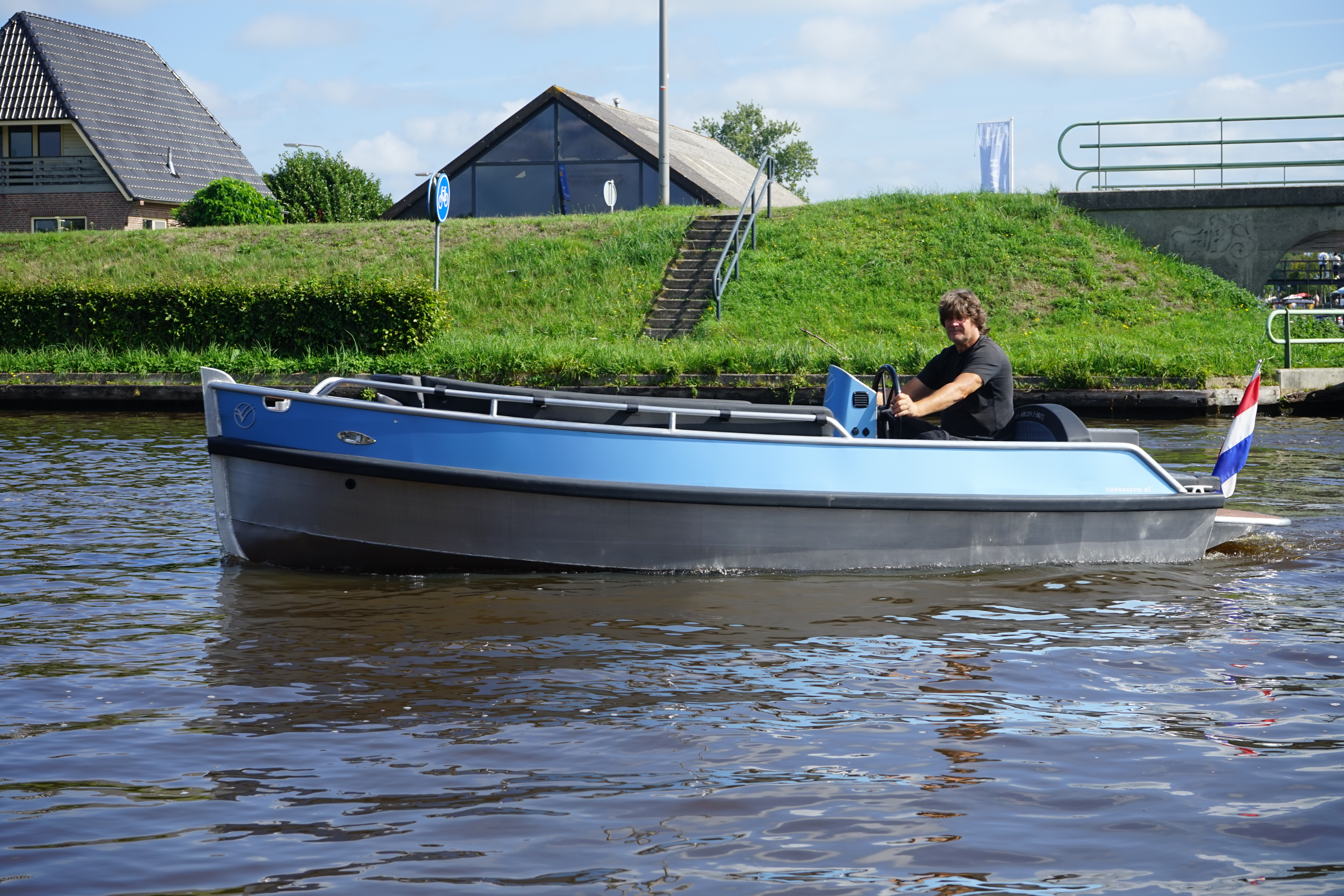 Zijaanzicht van de blauwe E-Tender 500 demoboot op het water